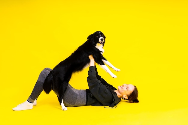 Disparo de una mujer deportiva en polainas con un perro border collie aislado sobre fondo amarillo y rojo