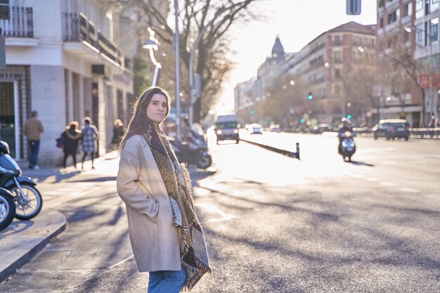 Foto disparo de una mujer joven y bonita cruzando la calle y mirando hacia los lados