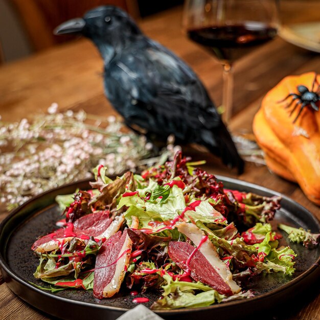 Disparo selectivo de una ensalada de tocino en un plato negro por un cuervo artificial