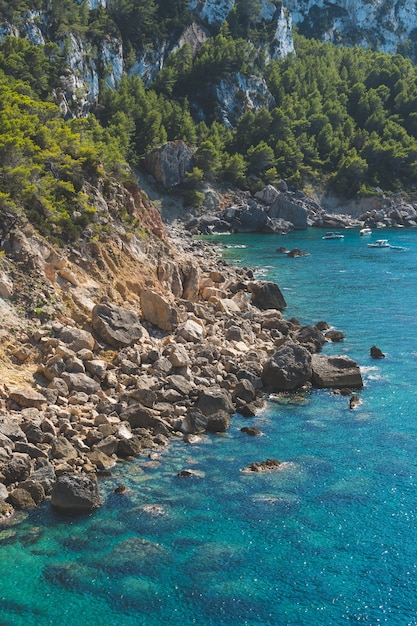 Disparo vertical de agua turquesa en una playa rocosa en Ibiza