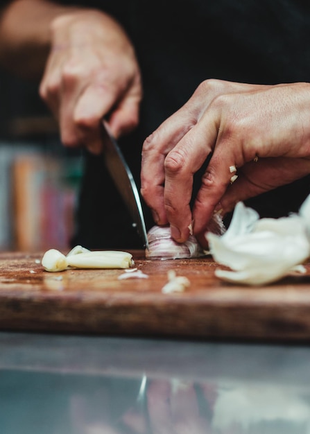 Disparo vertical de un chef cortando ajo en una mesa de madera