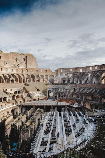 Disparo vertical del Coliseo bajo un cielo nublado y luz solar en Roma Italia