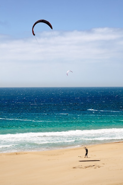 Disparo vertical de una cometa macho corriendo en una playa de arena