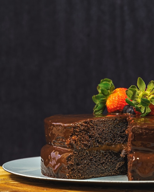 Disparo vertical de un delicioso pastel de chocolate decorado con fresas y arándanos