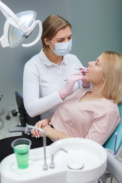 Disparo vertical de un dentista profesional examinando los dientes de la mujer joven