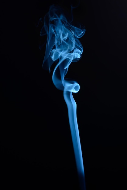 Un disparo vertical de humo de tabaco azul sobre un fondo negro