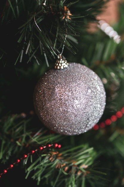 Disparo vertical de un juguete de Navidad gris brillante en un decorado de Nochevieja