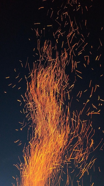 disparo vertical de llamas de fuego con chispas rojas ardientes volando contra el cielo nocturno oscuro