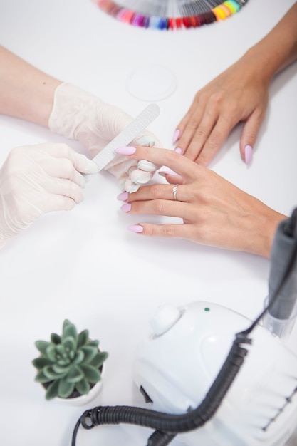 Foto disparo vertical de mujer irreconocible recibiendo manicura profesional en salón de belleza