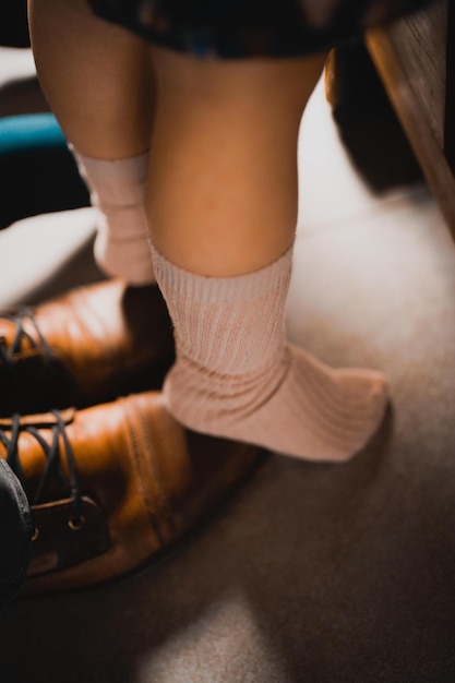 Disparo vertical de un niño de pie sobre los pies de su padre para aprender a caminar