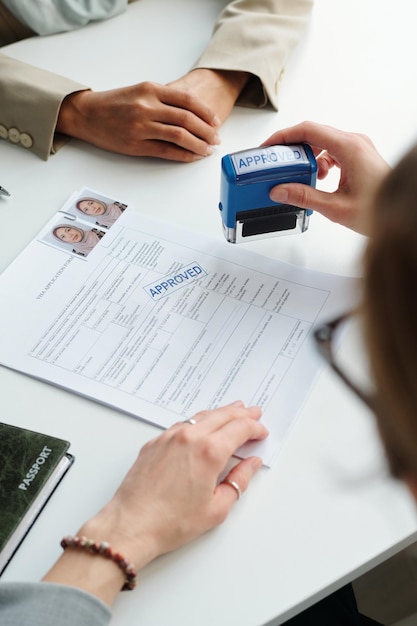 Foto disparo vertical de un oficial consular irreconocible que aprueba la visa de viaje para una mujer musulmana en em moderno