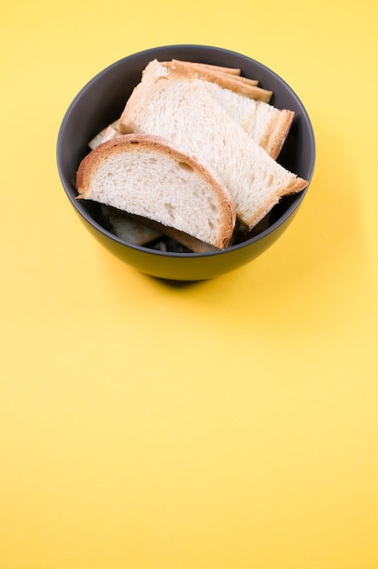 Disparo vertical de rebanadas de pan en un recipiente aislado sobre fondo amarillo