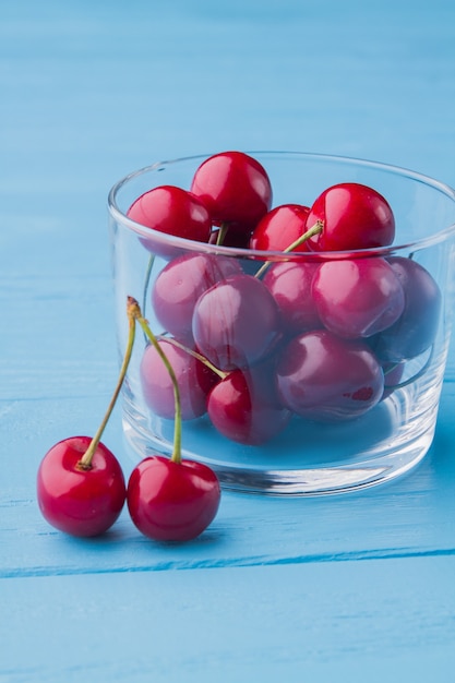 Disparo vertical de un vaso lleno de cerezas rojas maduras