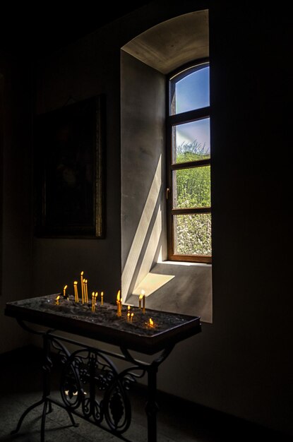 Disparo vertical de velas votivas encendidas junto a una ventana con luz solar