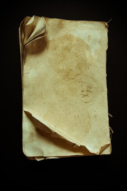 Disparo vertical de un viejo cuaderno de diario de papel en blanco desgastado aislado sobre un fondo negro
