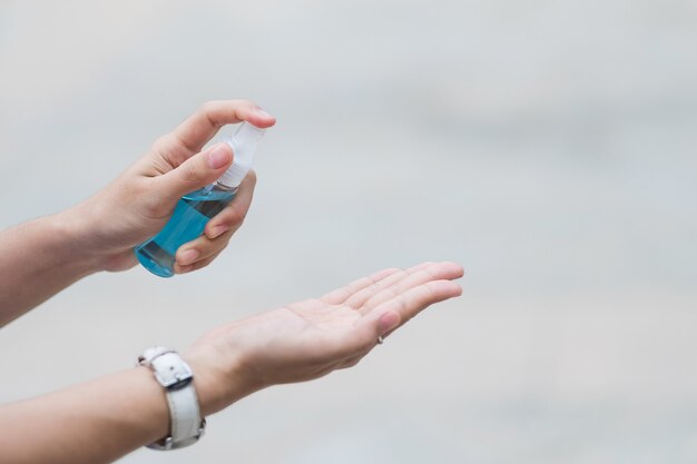 Dispensador de botella de desinfectante de alcohol para manos rociando a mano de mujer, contra coronavirus novedoso o enfermedad de virus corona (Covid-19) en público al aire libre.