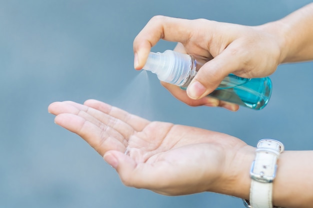 Dispensador de botella de desinfectante de alcohol rociado a mano de mujer, contra coronavirus novedoso o enfermedad de virus corona (Covid-19) en público al aire libre. Concepto antiséptico, de higiene y sanitario.