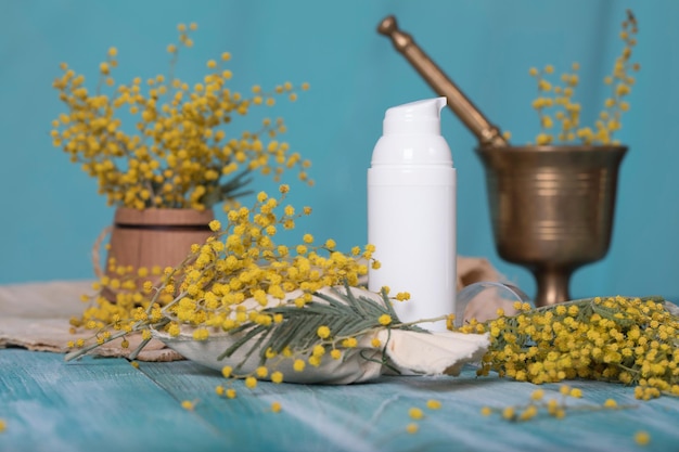 Dispensador de creme facial Mimosa em uma superfície de madeira ciano. Fechar-se