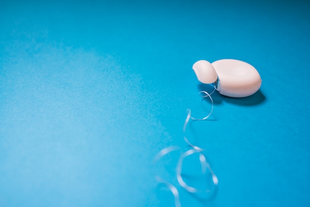 Dispensador de hilo dental para la higiene de la boca aislado en el fondo azul