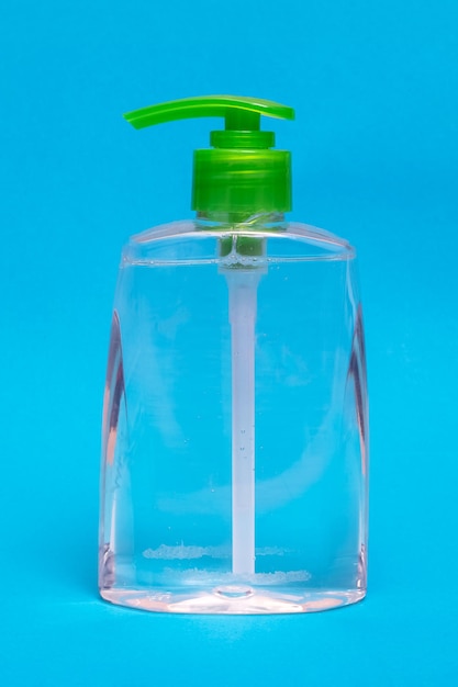 Dispensador de jabón líquido verde sobre fondo azul.