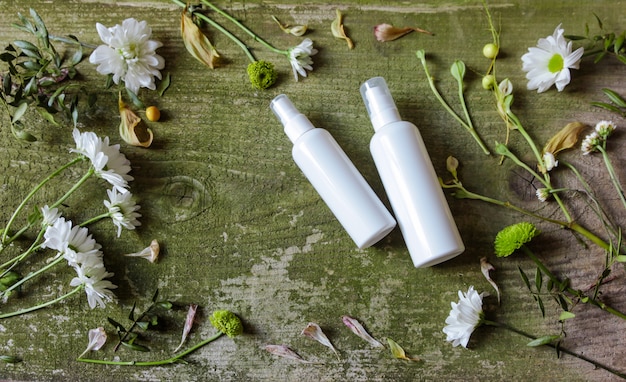 Dispensador de spray cosmético y flores sobre un fondo de madera