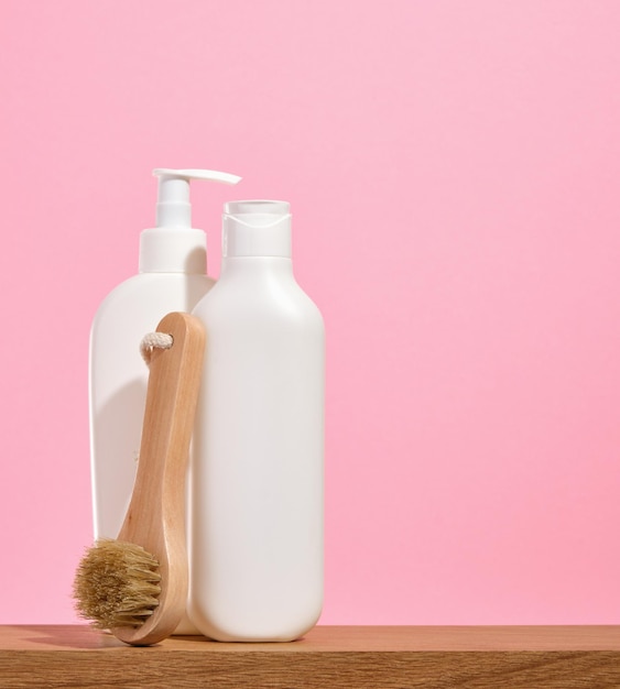 Foto dispensadores de champú blancos y una ducha redonda de madera o un pincel de masaje copiar espacio para el texto