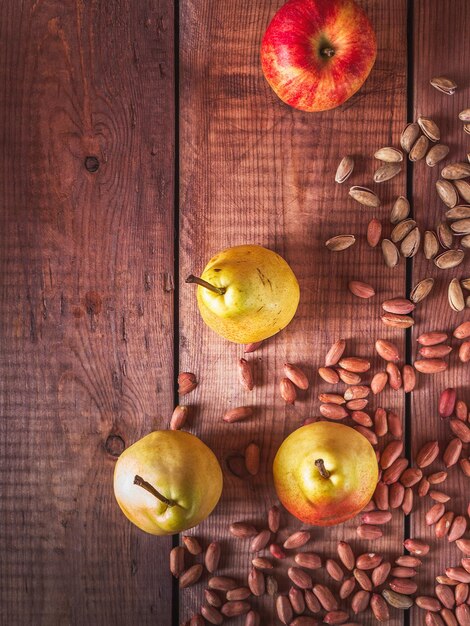 Foto dispersión de pistachos y cacahuetes peras y manzanas en la mesa vista superior