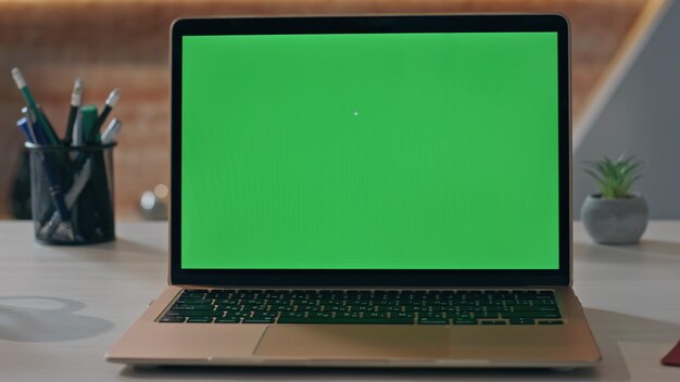 Display de laptop de chave de croma vazia no local de trabalho em close-up Computador de tela verde