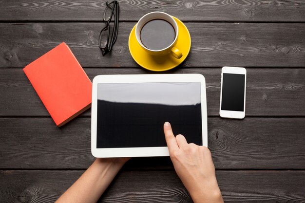 Dispositivo de tablet em branco sobre uma mesa de madeira com café