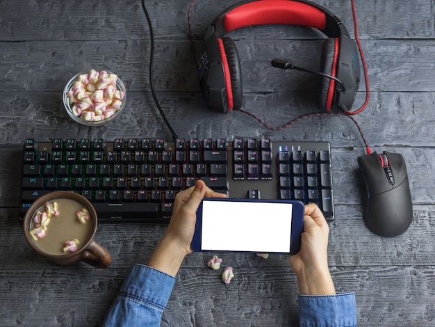 Dispositivo móvel nas mãos de uma criança em um fundo de mesa com instalações de computador