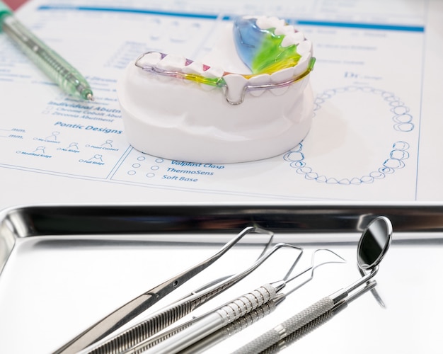 Dispositivo de ortodoncia retenedor dental y herramientas en el fondo de color.