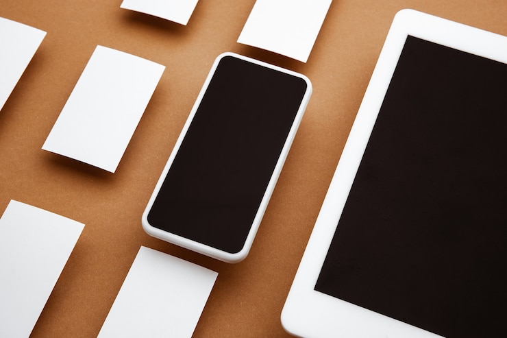 Foto dispositivo con pantalla en blanco flotando sobre un fondo marrón. teléfono, tableta y tarjetas. maqueta moderna con estilo de oficina para publicidad. copyspace blanco en blanco para el concepto de diseño, negocios y finanzas.