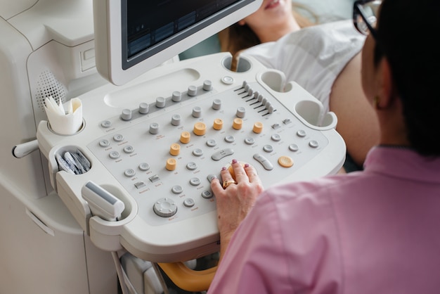 Dispositivo de ultrasonido de primer plano durante un examen médico de una mujer embarazada. Examen medico