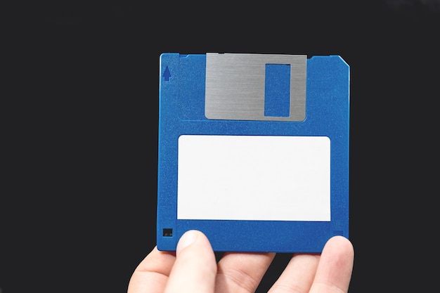 Disquete de computadora en mano sobre fondo negro