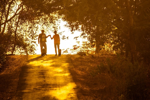 Foto distância média de amigos de pé na estrada em meio a árvores durante o pôr do sol