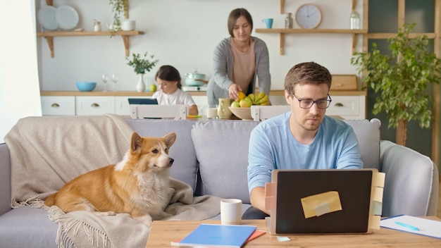 Distanciamento social. Um pai ocupado tenta trabalhar remotamente com seu filho e esposa em casa.