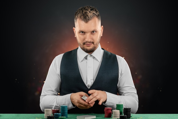 Distribuidor masculino en el casino en la mesa. Concepto de casino, juegos de azar, póquer, fichas en la mesa de casino verde.