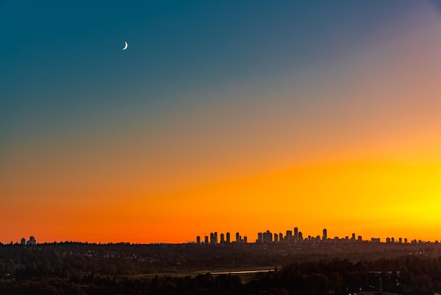 Distrito de Metrotown bajo la luna en el fondo del cielo al atardecer