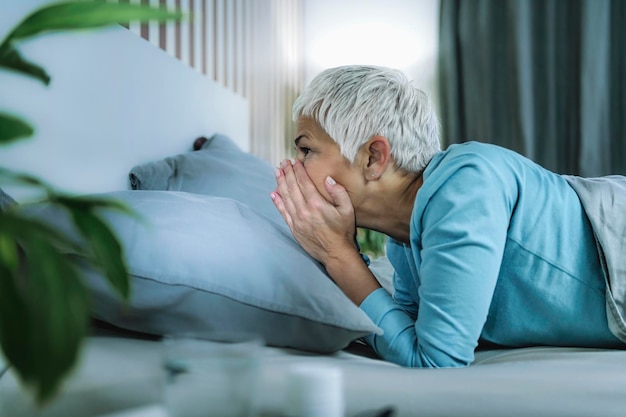 Foto distúrbio do sono do ritmo circadiano. mulher madura preocupada na cama, acordada até tarde da noite.