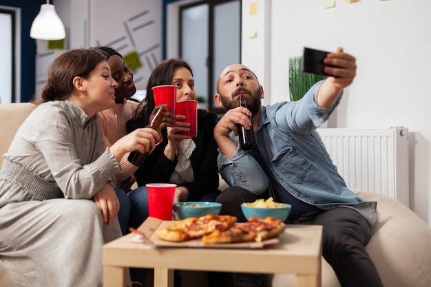 Diverrse grupo de compañeros de trabajo tomando selfie en smartphone