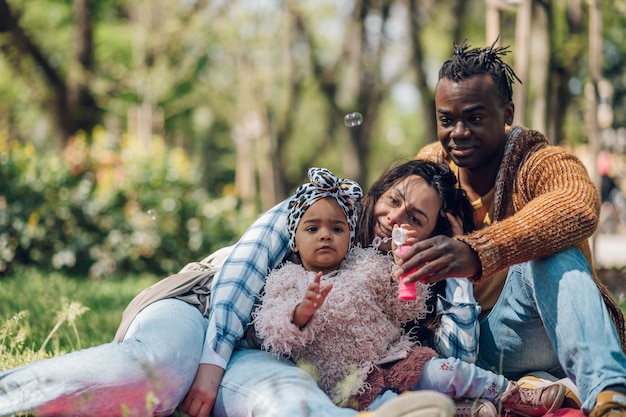 Diversa familia soplando pompas de jabón en el parque