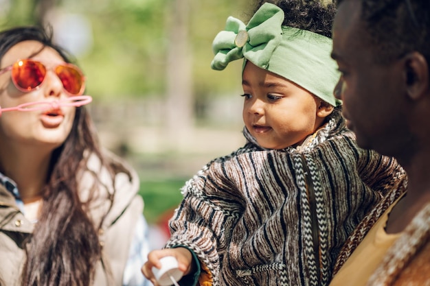 Diversa familia soplando pompas de jabón en el parque