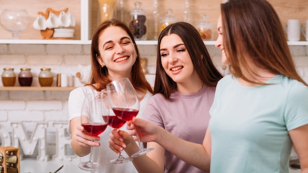 Diversão de festa feminina. celebração da amizade. mulheres jovens felizes tilintando taças de vinho tinto.