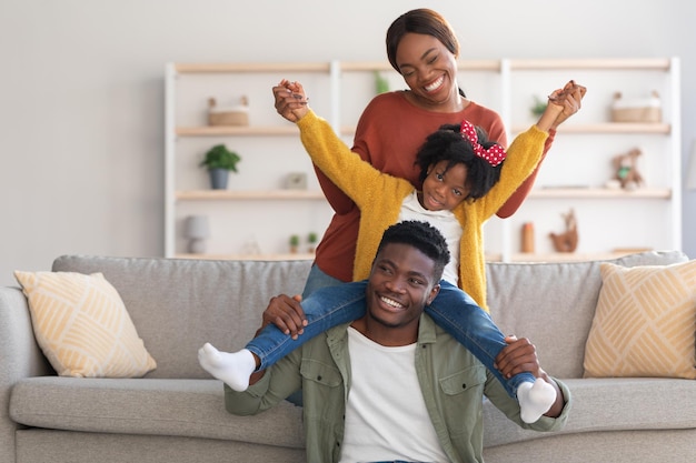 Diversão em casa alegre família afro-americana de três brincando na sala de estar