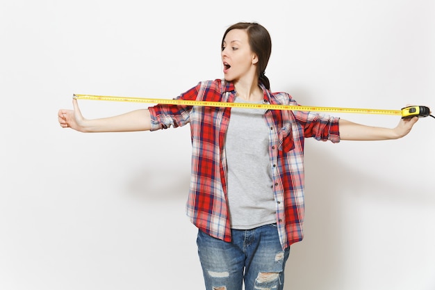 Foto diversão jovem mulher bonita em roupas casuais, segurando a fita métrica isolada no fundo branco. instrumentos, acessórios, ferramentas para sala de apartamento de renovação. conceito de casa de reparo. área de publicidade.