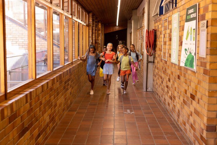 Foto diversas alunas felizes com sacos correndo e abraçando no corredor da escola primária