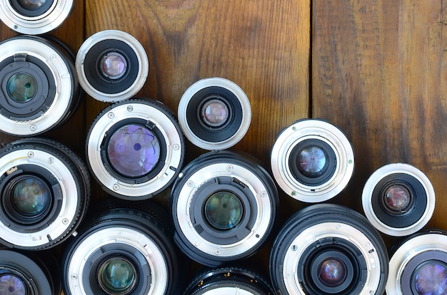 Diversas lentes fotográficas encontram-se em um fundo de madeira marrom.