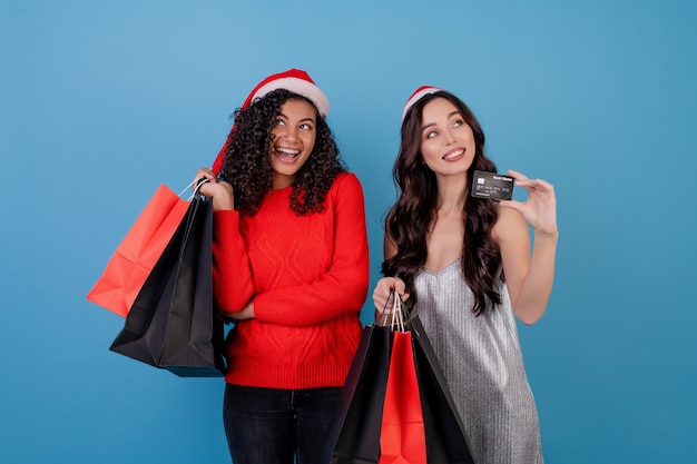 Diversas mujeres emocionadas con coloridos bolsos de compras y tarjeta de crédito