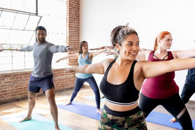 Diversas personas practicando una pose de yoga Virabhadrasana