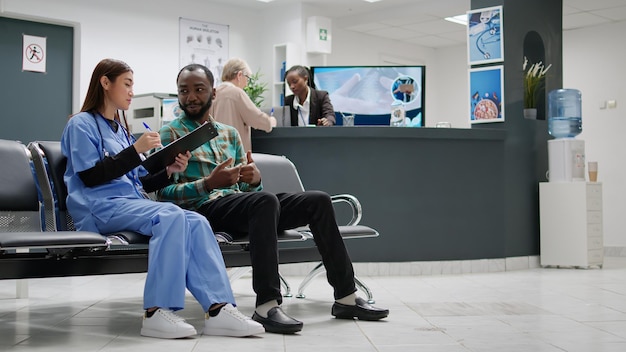 Diversas pessoas fazendo consultas na recepção do hospital, recebendo apoio de saúde e conselhos para curar doenças. paciente e enfermeira asiática falando sobre recuperação na área de espera.